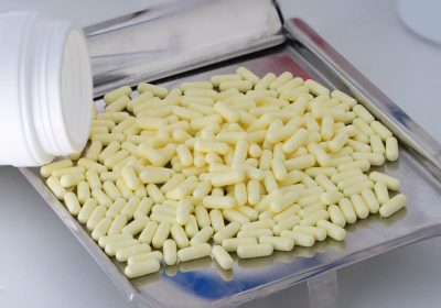 yellow capsules in medicine tray with pour plastic jar on count